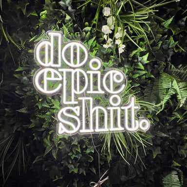 Do Epic Stuff Neon Sign in snow white on plant wall background