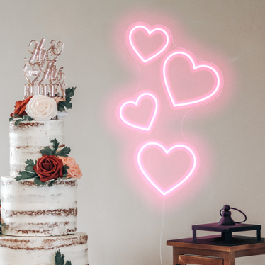 Pastel pink Floating Hearts Neon Sign behind a wedding cake