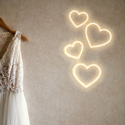 Floating Hearts Neon Sign in cosy warm white next to a white wedding dress