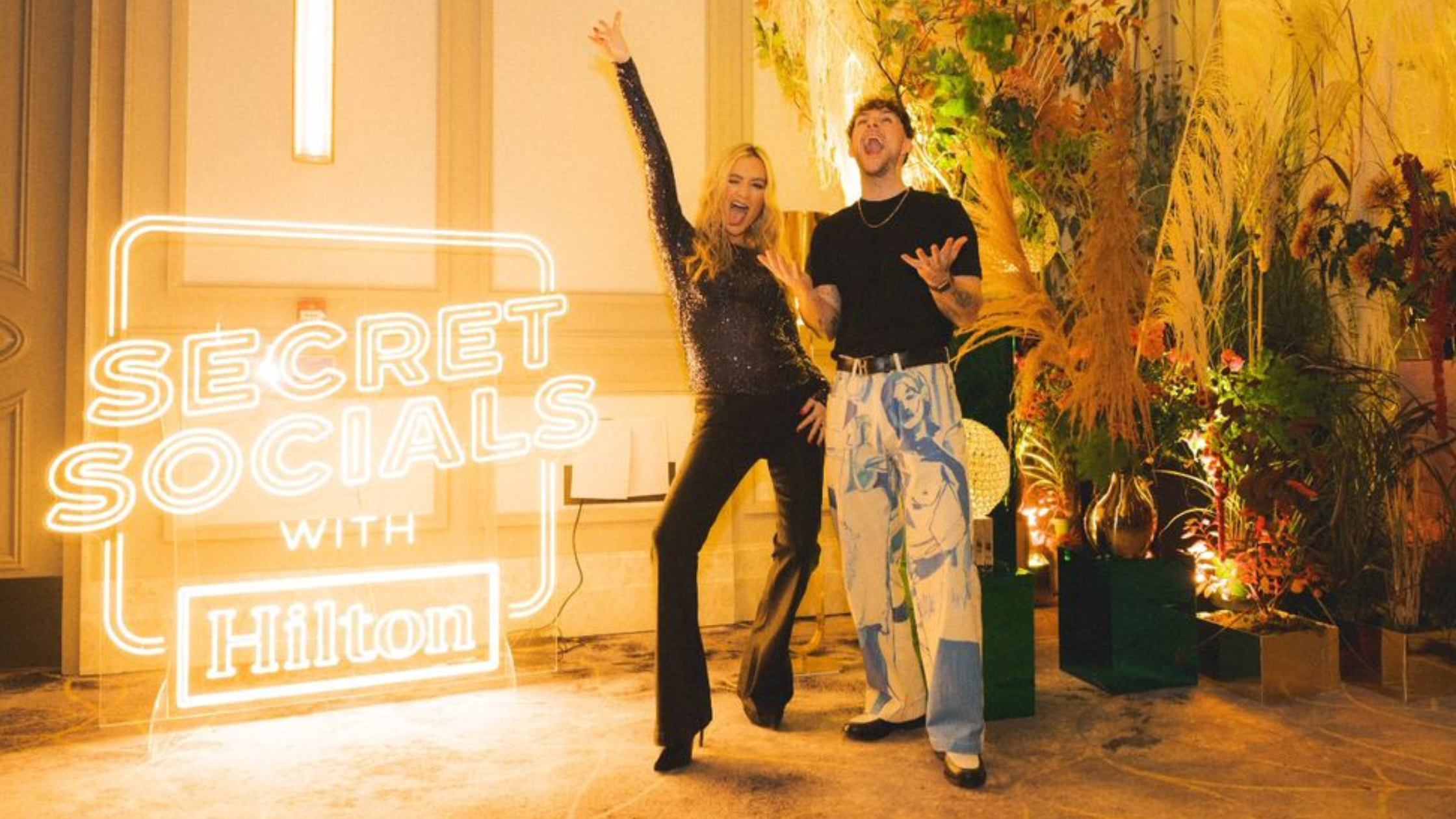 Hilton Secret Socials neon logo sign with Laura Whitmore and Tom Grennan.