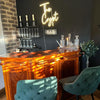 Home bar with real corner bar, glasses on wall, bar stools and white "The Crypt" neon bar sign