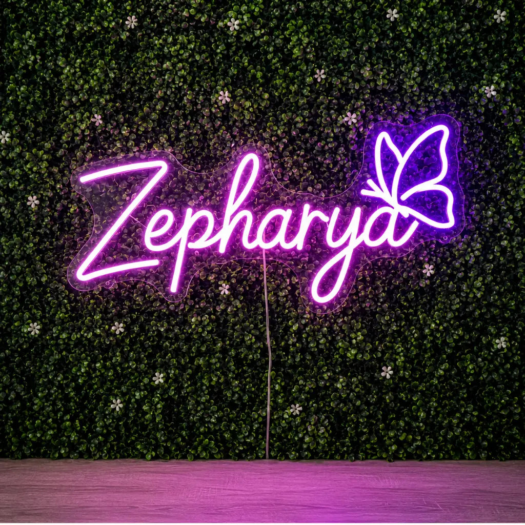 A neon-style sign spelling "Zepharya" in glowing pink-purple lettering with a butterfly motif on the right, mounted against a green leafy wall backdrop.
