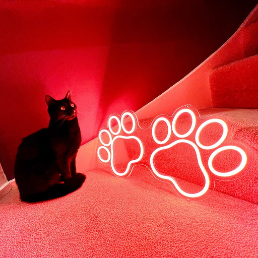 Red Paw Print Neon Sign next to a black cat.