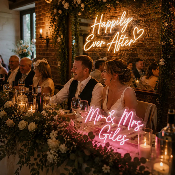 A wedding reception scene with a bride and groom seated at a decorated head table, surrounded by guests in a warmly lit brick-walled hall. Neon signs on the table read 'Happily Ever After' and 'Mr.