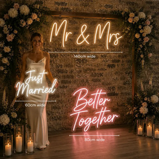 A styled wedding backdrop scene with a woman in a white gown standing beside a large glowing neon sign that reads 'Mr & Mrs'. Additional neon signs read 'Just Married' and 'Better Together' with width measurements overlaid.