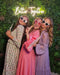 Three women posing against a plant backdrop with a custom neon sign saying "Better Together"