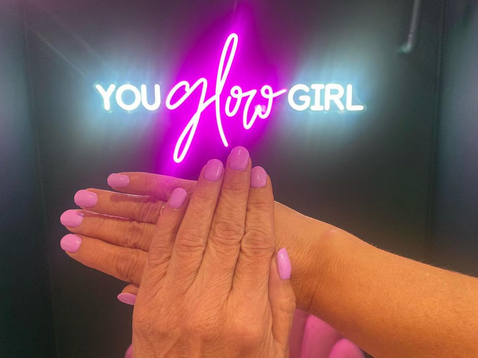 You glow girl neon sign with painted nails in front.
