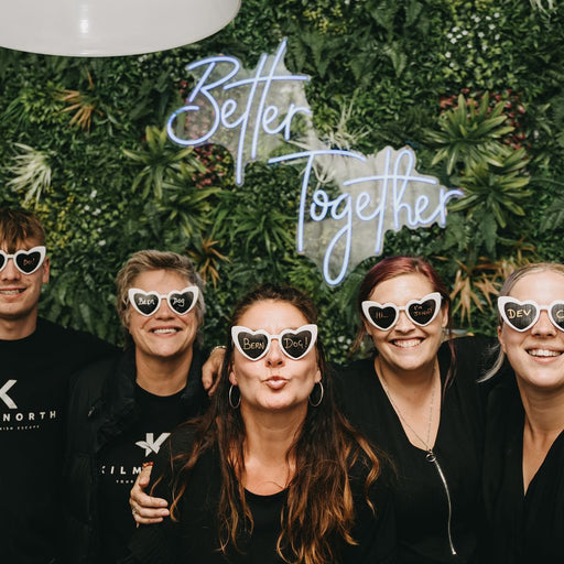 Wedding goers in front of a Blu "Better Together" neon sign