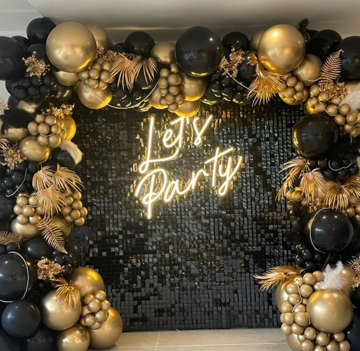 "Let's Party" neon sign in black and gold balloon arch. Image from @ occasionsbytori on Instagram