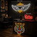 Three neon wall signs displayed in a tattoo studio setting: a large winged heart sign reading 160cm wide, a red 'Tattoo' script sign reading 60cm wide, and a tiger head sign reading 80cm wide. The studio features a dark wood counter, tattoo chair, and framed artwork on the wall.