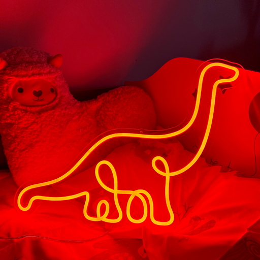 Hot Mama Red single line Diplodocus Dinosaur Neon Sign laid against a pillow and cuddly toy