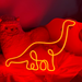 Hot Mama Red single line Diplodocus Dinosaur Neon Sign laid against a pillow and cuddly toy