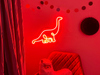 Bright orange single line Diplodocus Dinosaur Neon Sign mounted on the wall of a child's playrooms