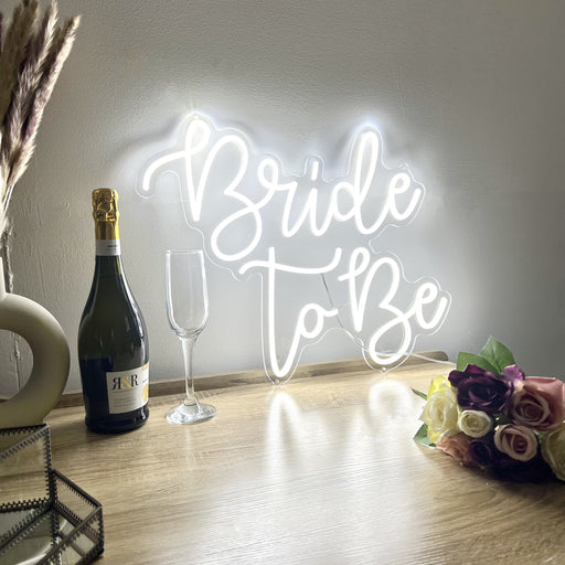 Bride to be neon sign next to champagne