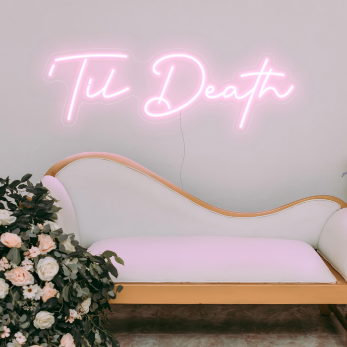 Til Death neon sign in pastel pink over a classy cream sofa