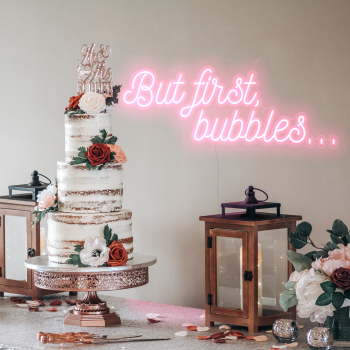Pastel pink but first, bubbles... neon sign over a wedding cake